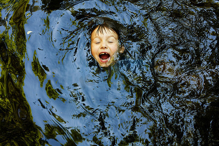 笑着的男孩在河里游泳