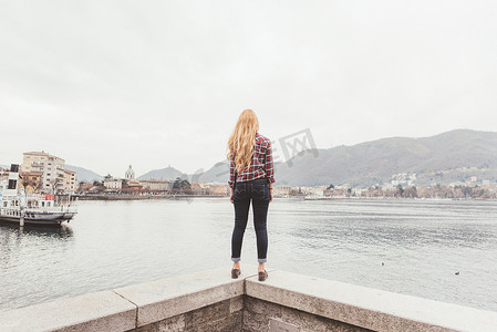 站在港口墙上向外眺望的年轻女子的后景科莫湖意大利