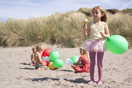 英国威尔士海滩上拿着气球吃冰激凌的女孩