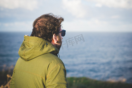民族风背景摄影照片_一名中年男子在多风的海岸上眺望大海意大利撒丁岛索尔索萨萨里