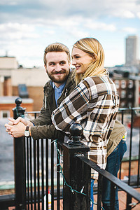 追逐摄影照片_幸福的年轻夫妇从城市屋顶露台向外眺望