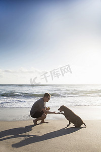 中年男人和狗在海滩上男人和狗握手