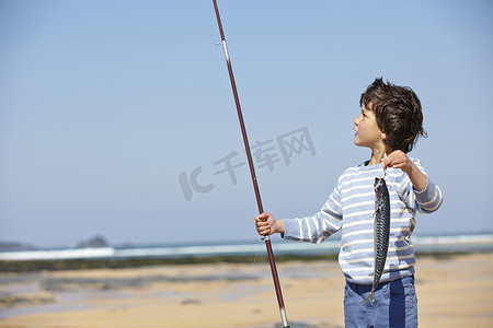 小男孩举着钓鱼竿和鱼