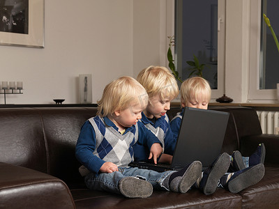 公司文化牌摄影照片_三个蹒跚学步的孩子在笔记本电脑上工作