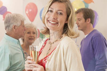 派对上的一名女子手持香槟长笛微笑着看着镜头