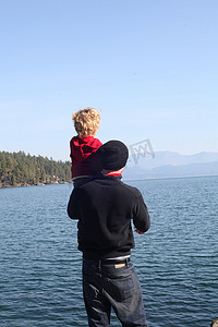 父亲和蹒跚学步的女儿看着湖对岸的景色