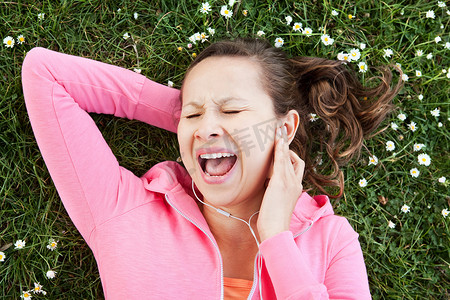 一名女子在草地上对着耳机唱歌