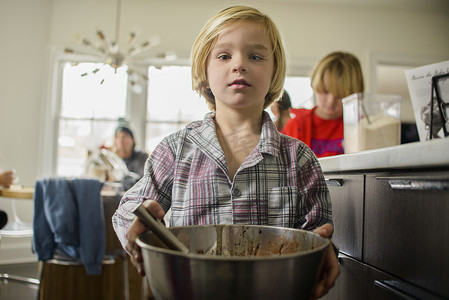 男孩在厨房里拿着搅拌碗的肖像