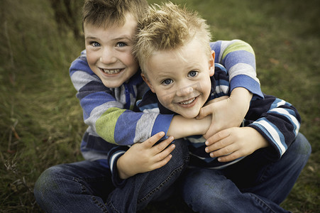 男孩们坐在草地上拥抱看着镜头微笑的剪影