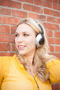 游戏红砖墙摄影照片_戴着耳机的女子靠在砖墙上的特写