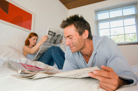 夫妇在床上看报纸