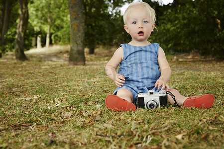 测速仪摄影照片_坐在草地上的女婴拿着胶卷相机张开着相机嘴
