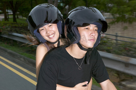 疫情防控青年摄影照片_骑着轻便摩托车的年轻亚洲夫妇