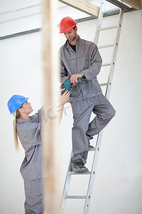 建筑蓝红摄影照片_建筑工地上手持电钻的男女工人