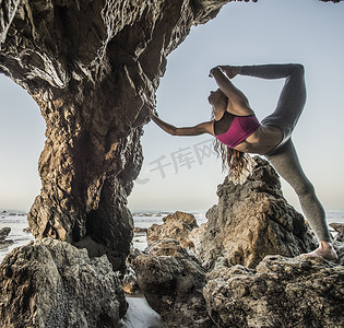 在美国加利福尼亚州洛杉矶的海蚀洞上年轻的女舞者单腿站立