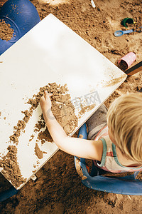 俯瞰坐在沙坑里的男孩玩沙子的桌子