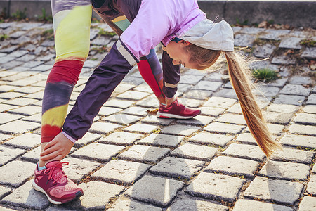 中年女子跑步者在鹅卵石上做热身运动