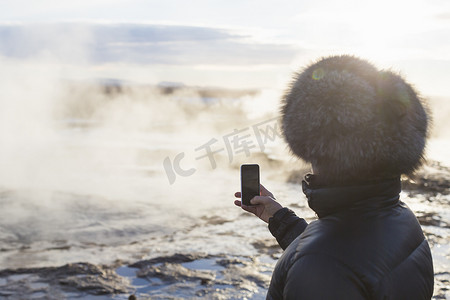 位于冰岛西南部山坡上的山谷中的间歇泉拍摄大间歇泉的女子