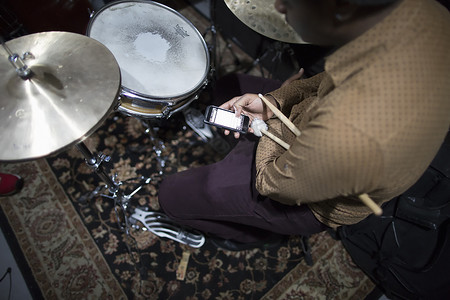鼓手坐在鼓包前使用智能手机