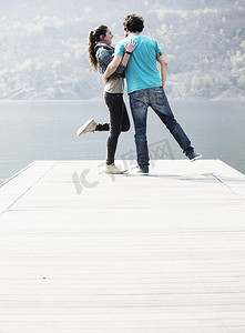 意大利皮埃蒙特韦尔巴尼亚的梅尔戈佐湖一对年轻夫妇单腿站在码头上