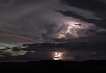 神木出云摄影照片_一股强大的上升气流从平流层反弹形成了一个巨大的不断膨胀的砧状云上升气流中射出的闪电照亮了地平线