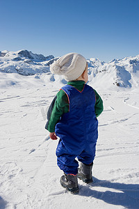 站在雪地里望着群山的小男孩