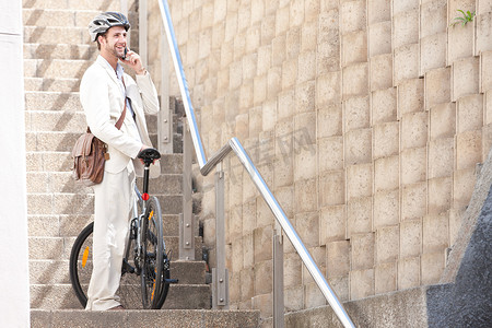 楼梯防护摄影照片_骑着自行车踩着手机的年轻人
