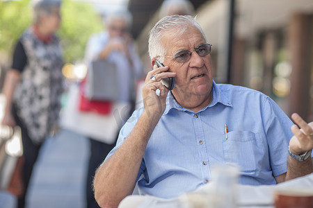 老人技术摄影照片_一位老人坐在咖啡馆外用手机