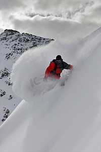 高山滑雪运动员摄影照片_滑雪运动员在厚厚的积雪中骑行