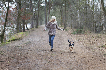 一名中年妇女带着她的狗在森林里跑步