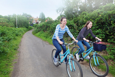 两个年轻的成年姐妹沿着乡间小路骑自行车