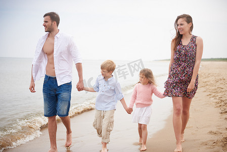 爱情阶段摄影照片_一家人手牵手走在海滩上