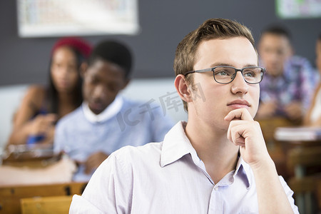 男学生肖像坐在教室的书桌前