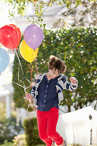 十岁的小女孩兴奋地拿着一堆气球跳着