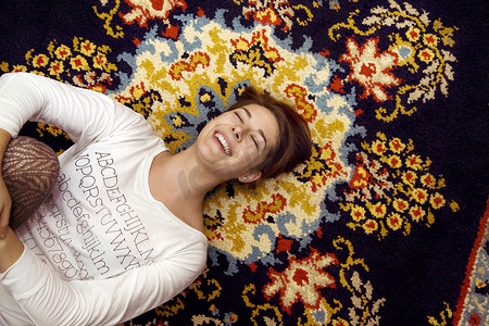 躺在花毯上的年轻女子笑着