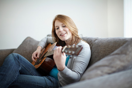 坐在沙发上弹吉他的女孩