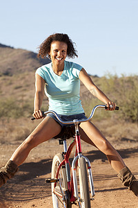 在沙漠中骑自行车下山的年轻女子的肖像