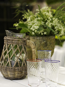 花园桌子上的复古柳条壶和饮水杯