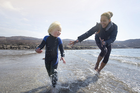 母亲和儿子在海滩上跑步埃肖特湖斯凯岛赫布里底群岛苏格兰