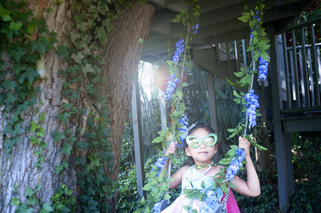 年轻女孩穿着奇装异服坐在树上荡秋千