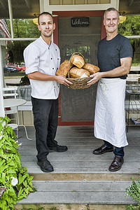 餐厅门前摆着一篮子面包的咖啡馆老板和厨师