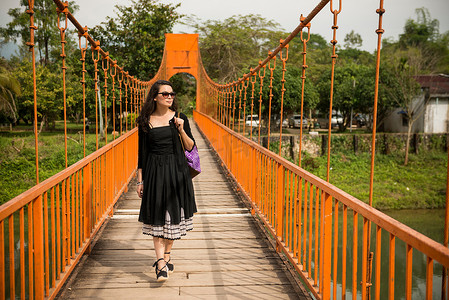 行走的女人摄影照片_老挝河上的桥上的女人