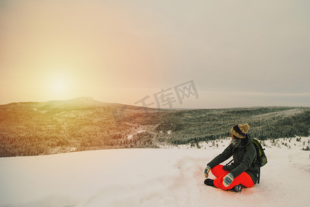 坐在白雪覆盖的风景上看山上日落的女人
