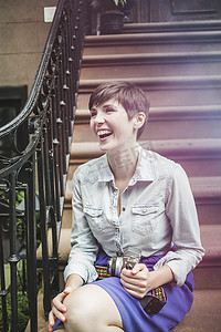 一名年轻女子坐在台阶上拿着相机美国纽约