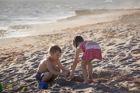男孩和妹妹在海滩上玩沙子美国佛罗里达州朱庇特岛吹石保护区