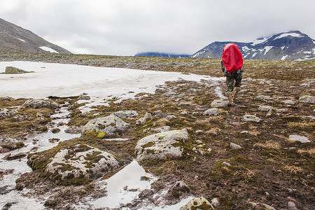 在俄罗斯乌拉尔山脉年轻人在冰冻的风景中徒步旅行的背影