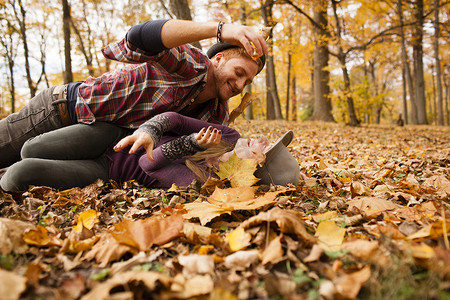 一对年轻夫妇在森林里玩秋叶打架