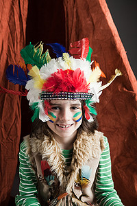 穿着美洲原住民服装的小男孩带着圆锥形帐篷