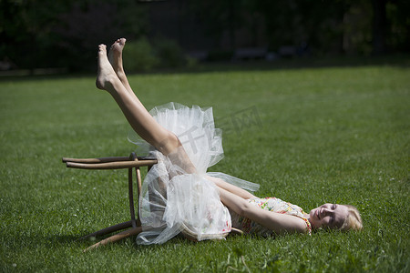 躺在草地上的年轻女子的肖像坐在跌倒的凳子上微笑着