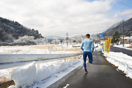 日本富士山川口湖冬季公路上跑步的成年男性运动员的背影